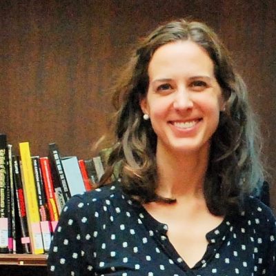 Whitney Arnold stands in front of a bookshelf.