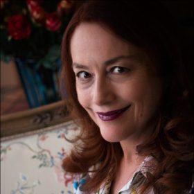 Headshot of Giulia Sissa in front of a floral couch.