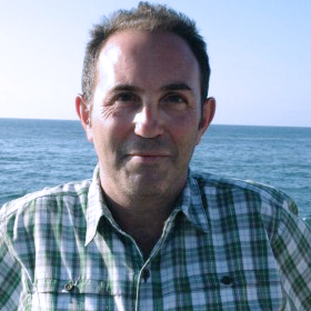 Saree Makdisi in a green plaid shirt standing in front of the ocean.
