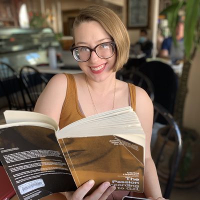 Rebecca Ogden Smith holds a book in her hand, The Passion According to G.H. by Clarice Lispector.