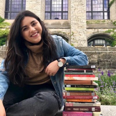Sophia Lencioni smiles and rests her elbow on top of a stack of books.